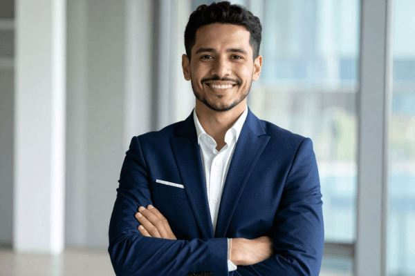 Confident business professional in a navy suit with arms crossed, representing a Designated Employer Representative (DER) managing a DOT drug and alcohol testing program.