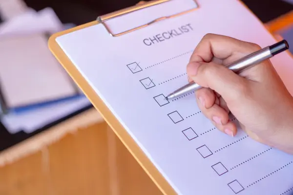 Hand checking items on a compliance checklist on a clipboard, representing the FMCSA drug and alcohol audit checklist motor carriers should maintain for DOT program documentation and audit readiness.