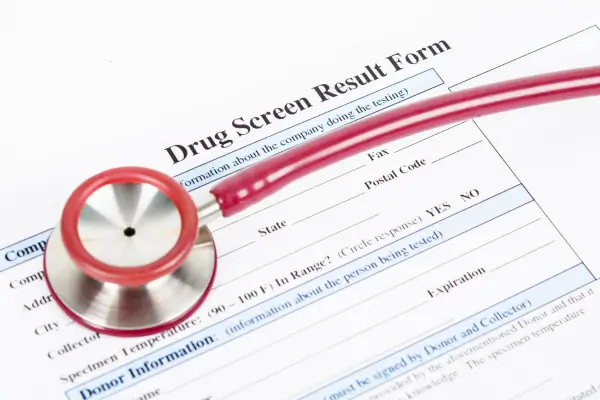 Drug screen result form with a red stethoscope, representing the DOT and workplace drug testing process Colorado employers must continue to follow regardless of federal marijuana rescheduling.