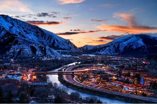 Aerial view of Glenwood Springs, Colorado at sunset with snow-capped mountains, the Colorado River, and the I-70 corridor — the location of PROCOM’s certified drug and alcohol testing office serving Garfield County employers.